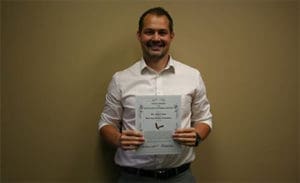 Cosmetic Dentist Dr. John Chase holding an award Minot ND